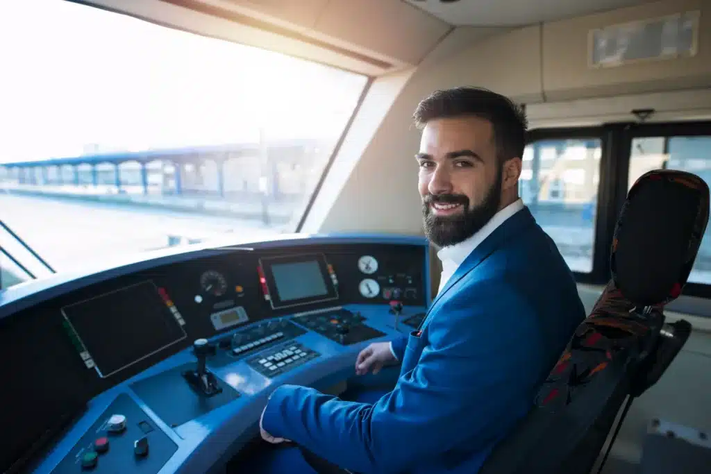 Piloto: uma profissão de alta remuneração Homem sorridente dentro da cabine de um trem, representando a profissão de piloto