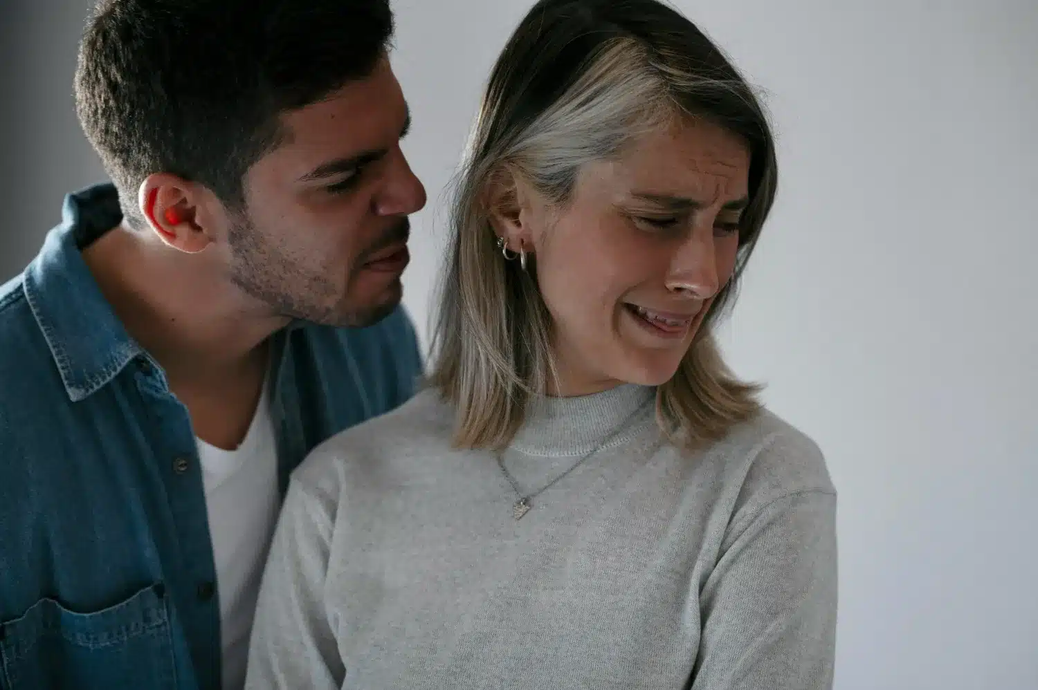 Homem se aproximando de mulher, ambos com expressões de desconforto, representando uma dinâmica manipuladora em um relacionamento.