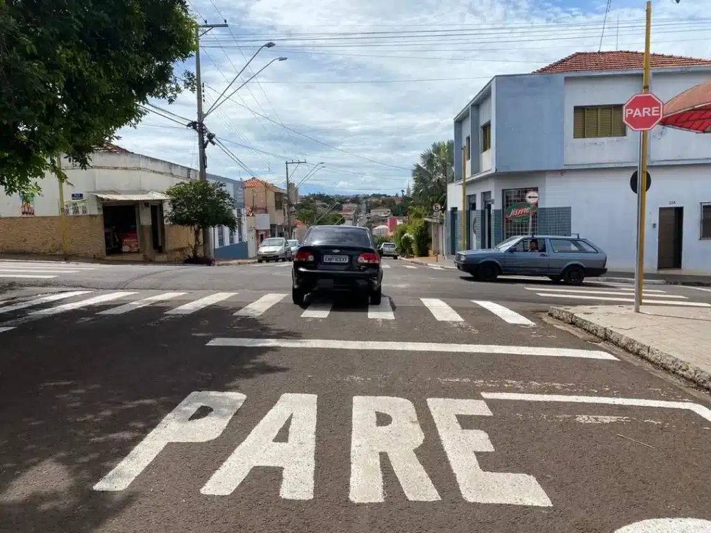 Prefeitura dCruzamento com sinalização de PARE: o impacto das placas no trânsito Imagem de um cruzamento com sinal de 'PARE' visível no asfalto, destacando a importância da sinalização no trânsito