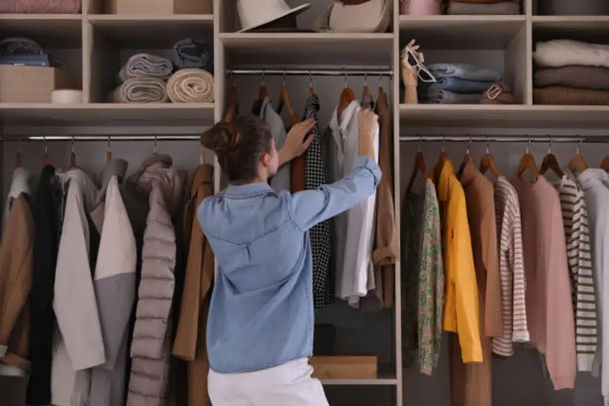 Pessoa organizando o guarda-roupa, escolhendo roupas, refletindo sobre estilo e bem-estar emocional