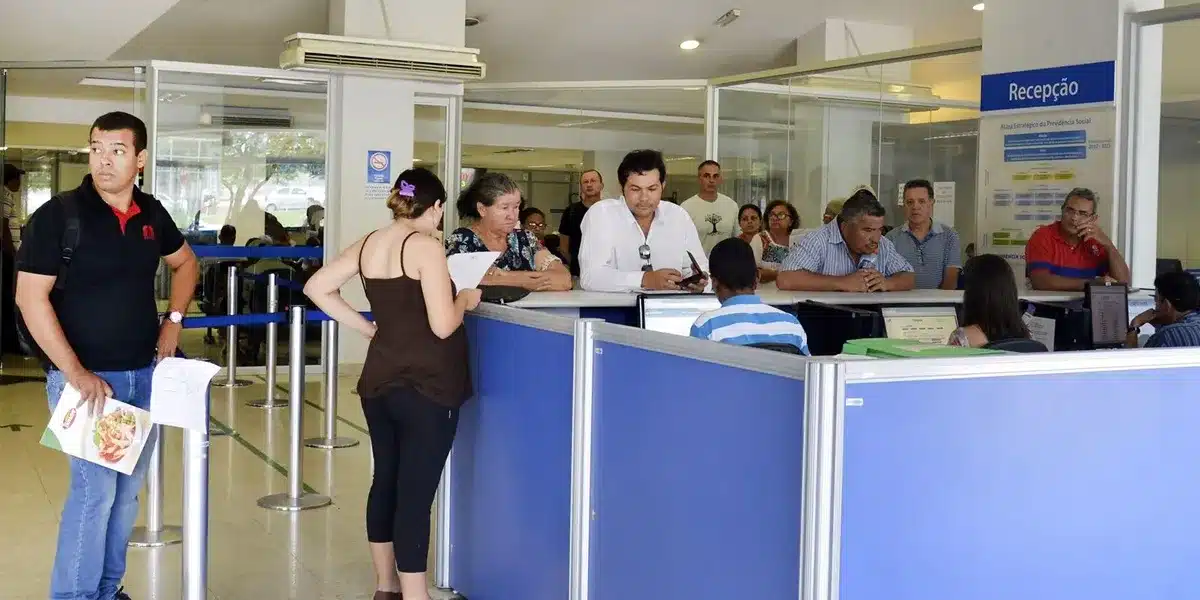 Pessoas aguardando atendimento em uma agência do INSS, com destaque para o fechamento das agências no Dia do Trabalhador.