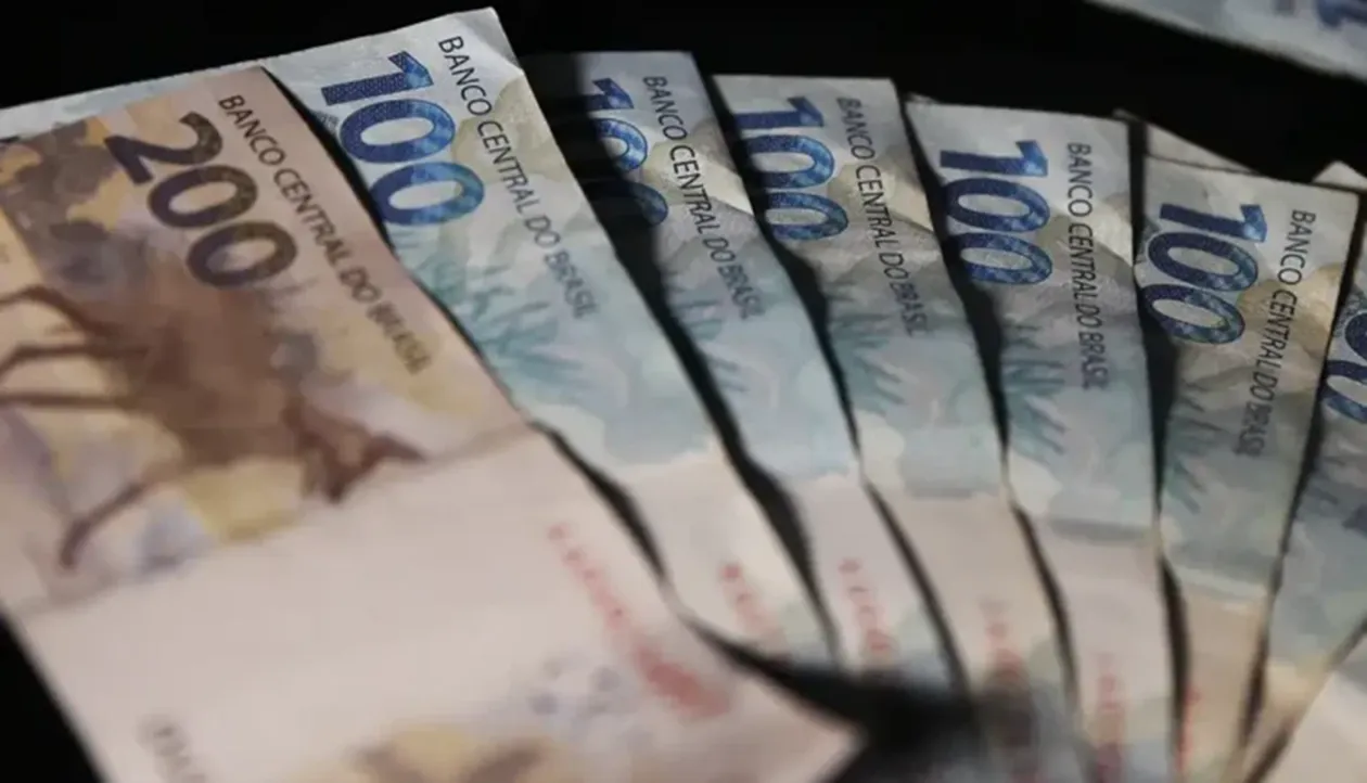 Notas de dinheiro do Banco Central do Brasil, incluindo cédulas de R$ 100 e R$ 200, representando os pagamentos do INSS.