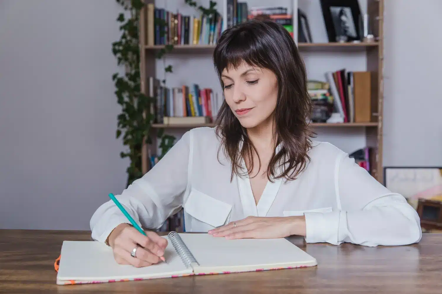 Entendendo o Uso Impessoal do Verbo 'Fazer Mulher concentrada escrevendo em um caderno, simbolizando o estudo e o aprendizado do uso impessoal do verbo 'fazer' na língua portuguesa.