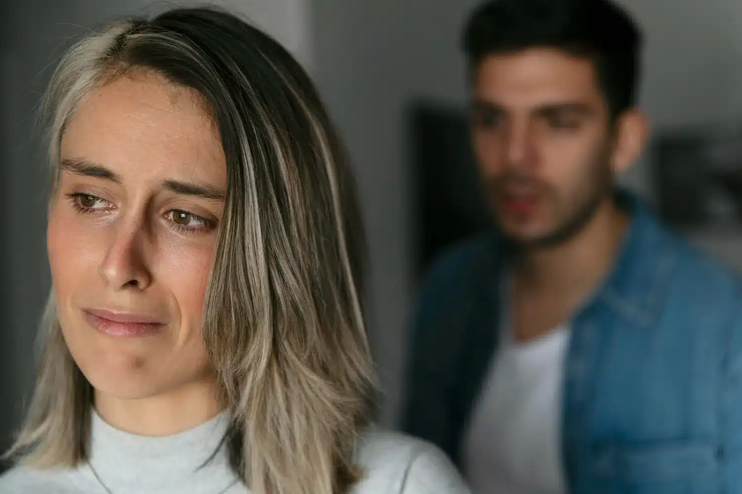 Inversão de culpa em manipulação emocional Mulher com expressão de tristeza e culpa em discussão com parceiro.