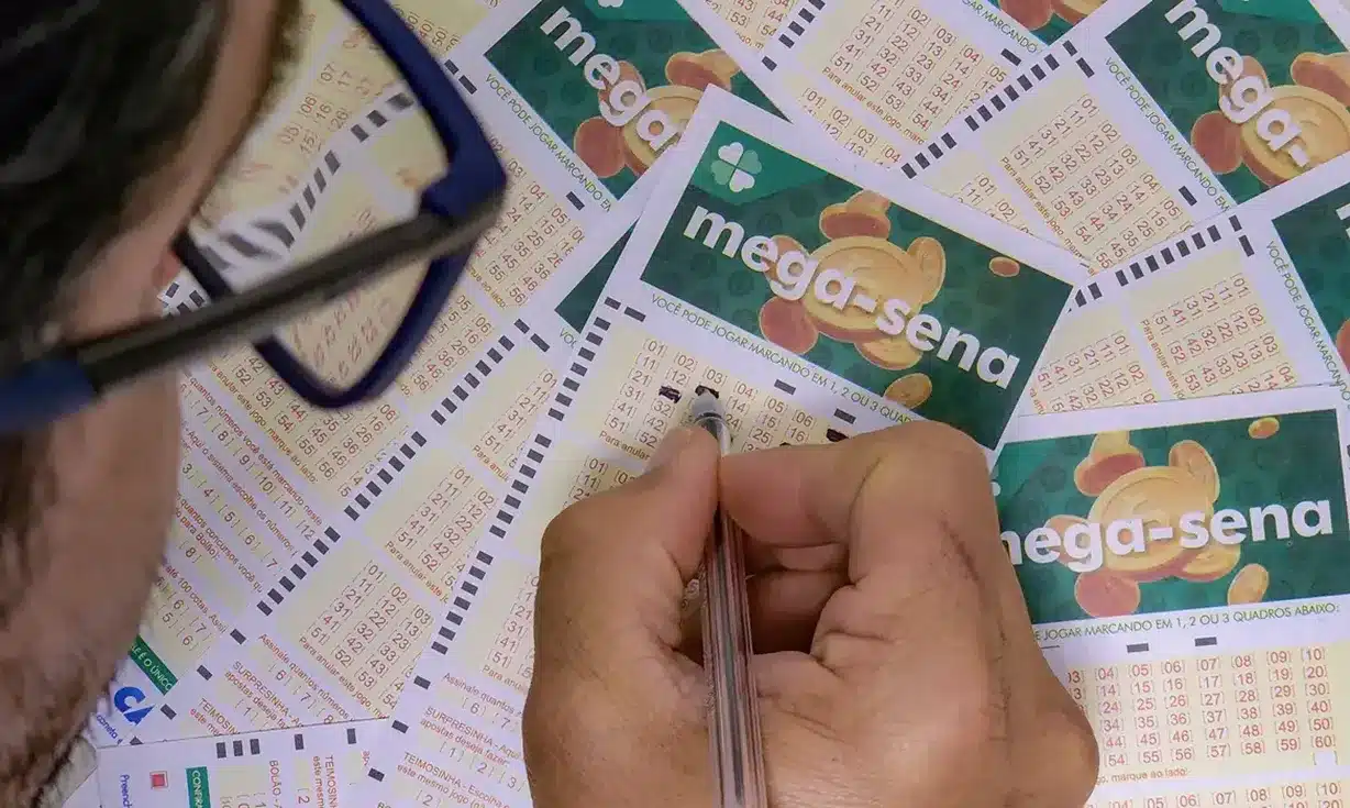 Apostador escolhendo seus números para o próximo sorteio da Mega-Sena. essoa marcando os números na ficha da Mega-Sena, com foco nos bilhetes.
