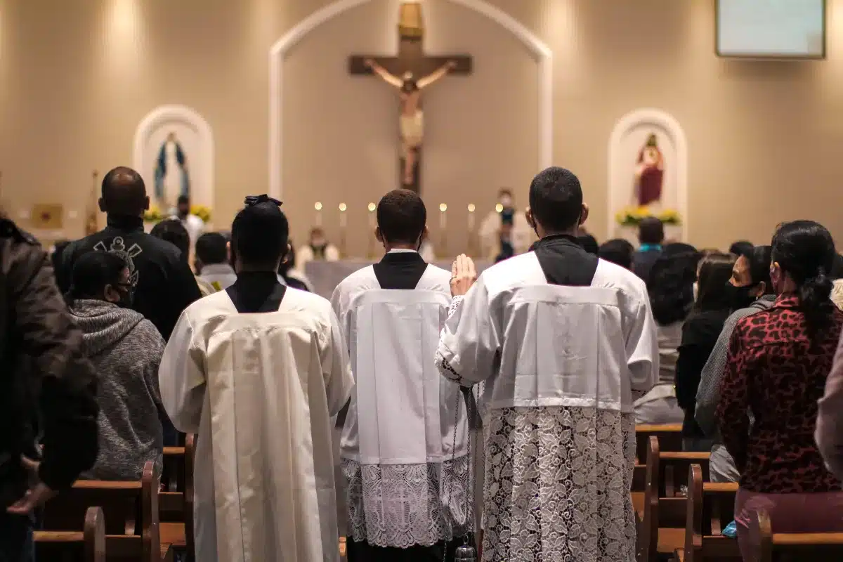 Missa e fé: momento de oração e comunhão Fiéis participando de uma missa com o altar ao fundo e cruz.