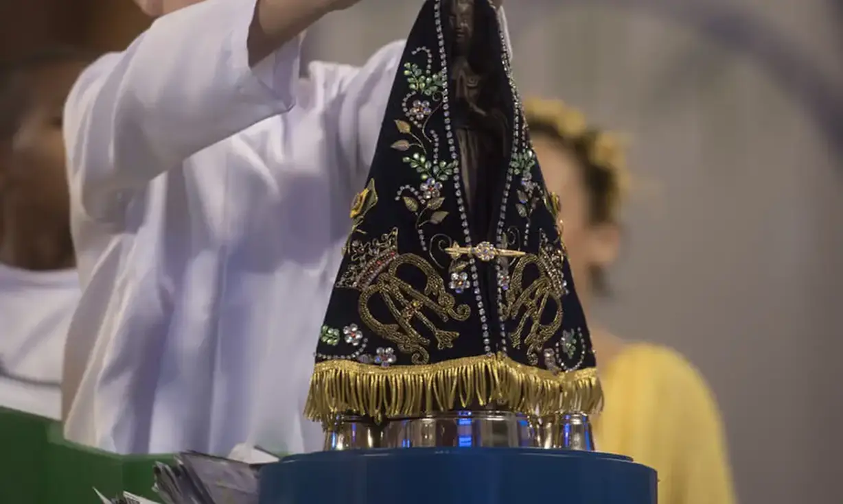 Nossa Senhora Aparecida: Feriado de Fé e Devoção Nacional. Imagem de Nossa Senhora Aparecida, padroeira do Brasil, sendo erguida durante celebração religiosa.