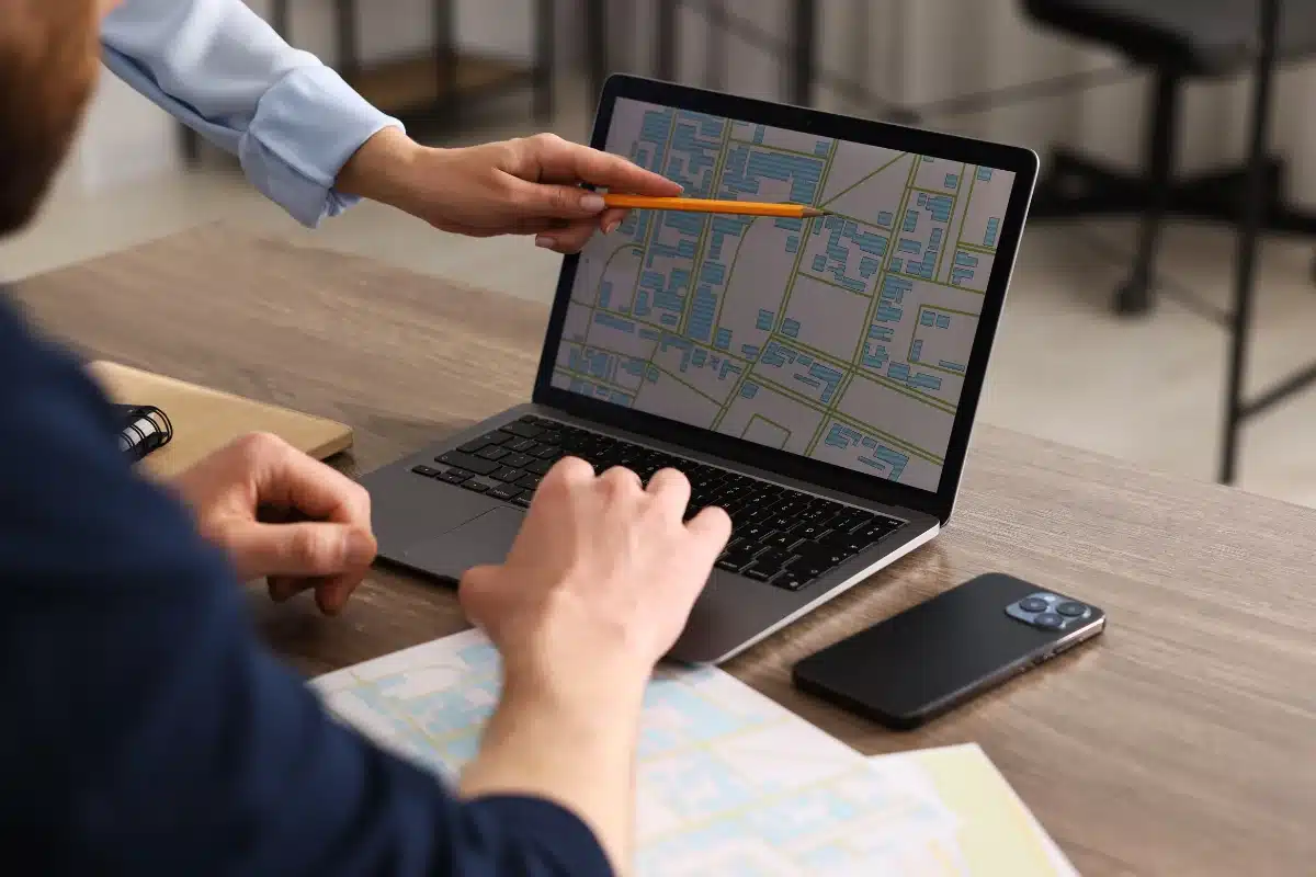 Profissão de Cartógrafos Profissional apontando para o mapa em um laptop durante reunião.