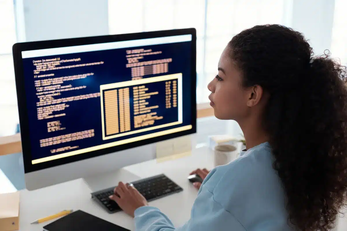 Programadora analisando códigos em desenvolvimento de software Profissional programadora analisando códigos em tela de computador, trabalhando com desenvolvimento de software.