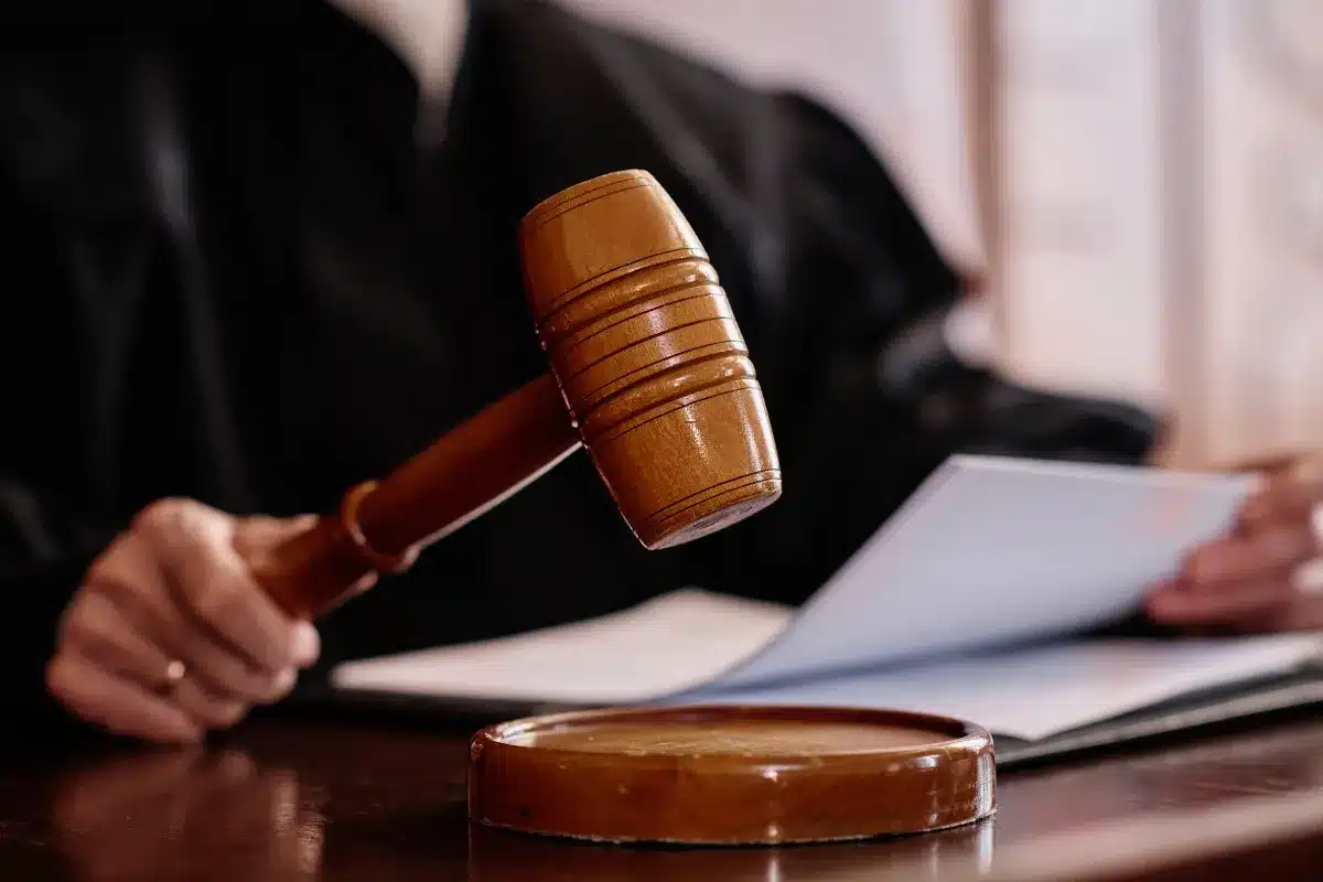 Profissão de Juiz Martelo de juiz sendo levantado durante audiência judicial, simbolizando a tomada de decisões legais.