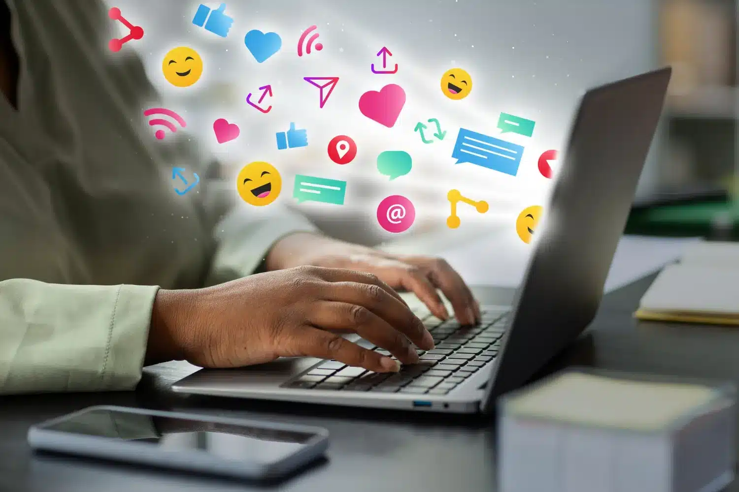 Pessoa digitando no computador com ícones coloridos de redes sociais e comunicação ao redor.