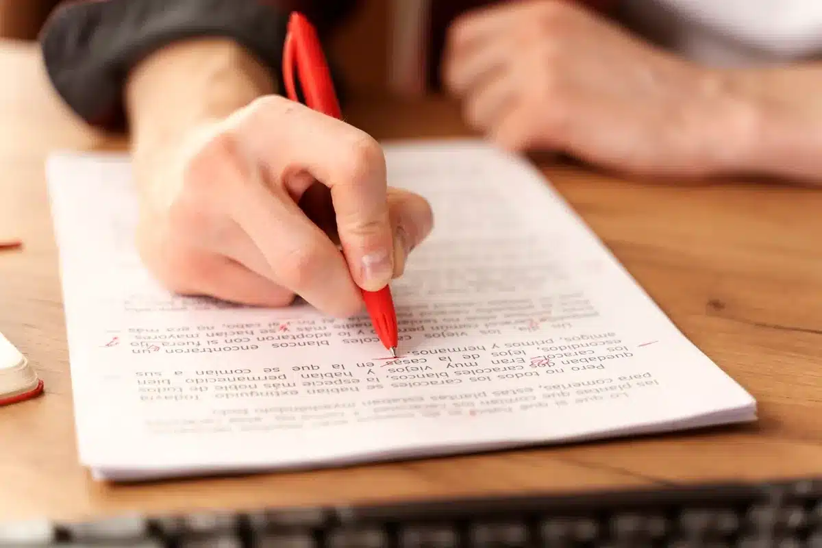 Preparação para a prova objetiva do concurso de 2025. Pessoa revisando um documento enquanto se prepara para o concurso de 2025.