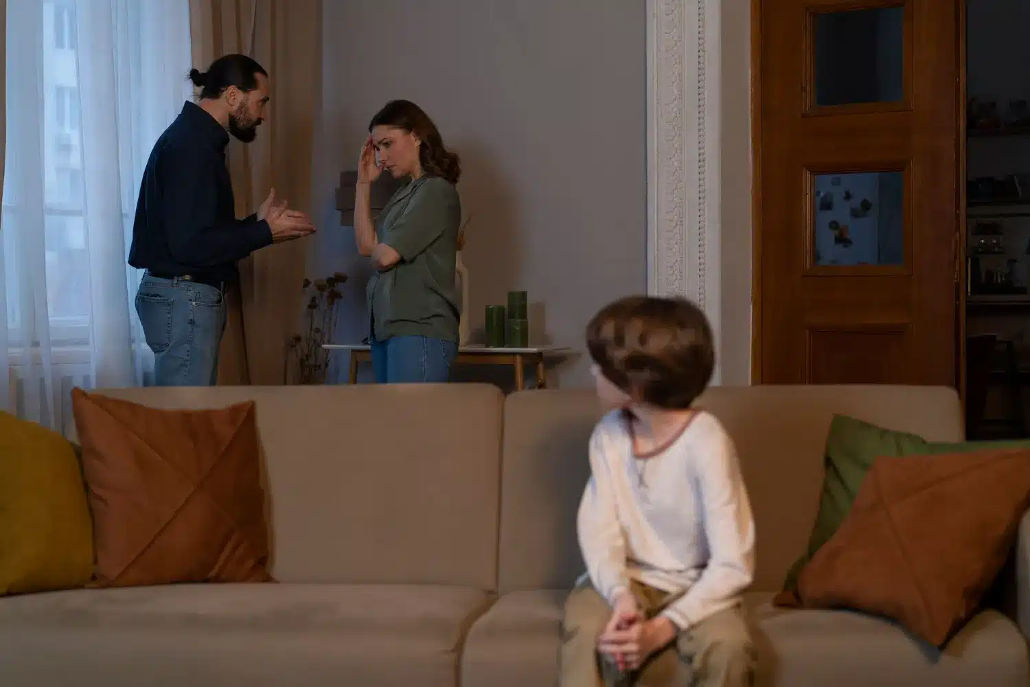 Imagem de um casal discutindo enquanto seu filho observa, refletindo um ambiente familiar tenso e disfuncional.