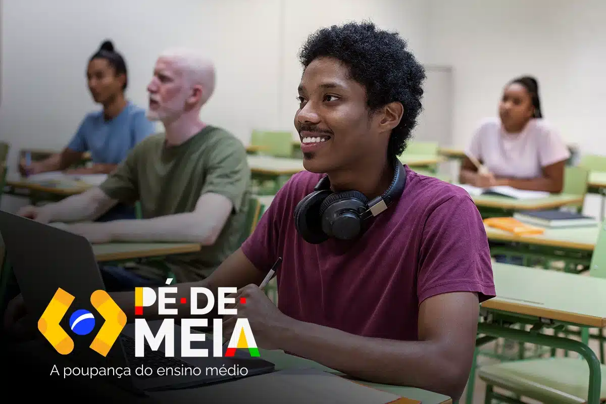 Estudante sorridente com fones de ouvido em sala de aula usando laptop.