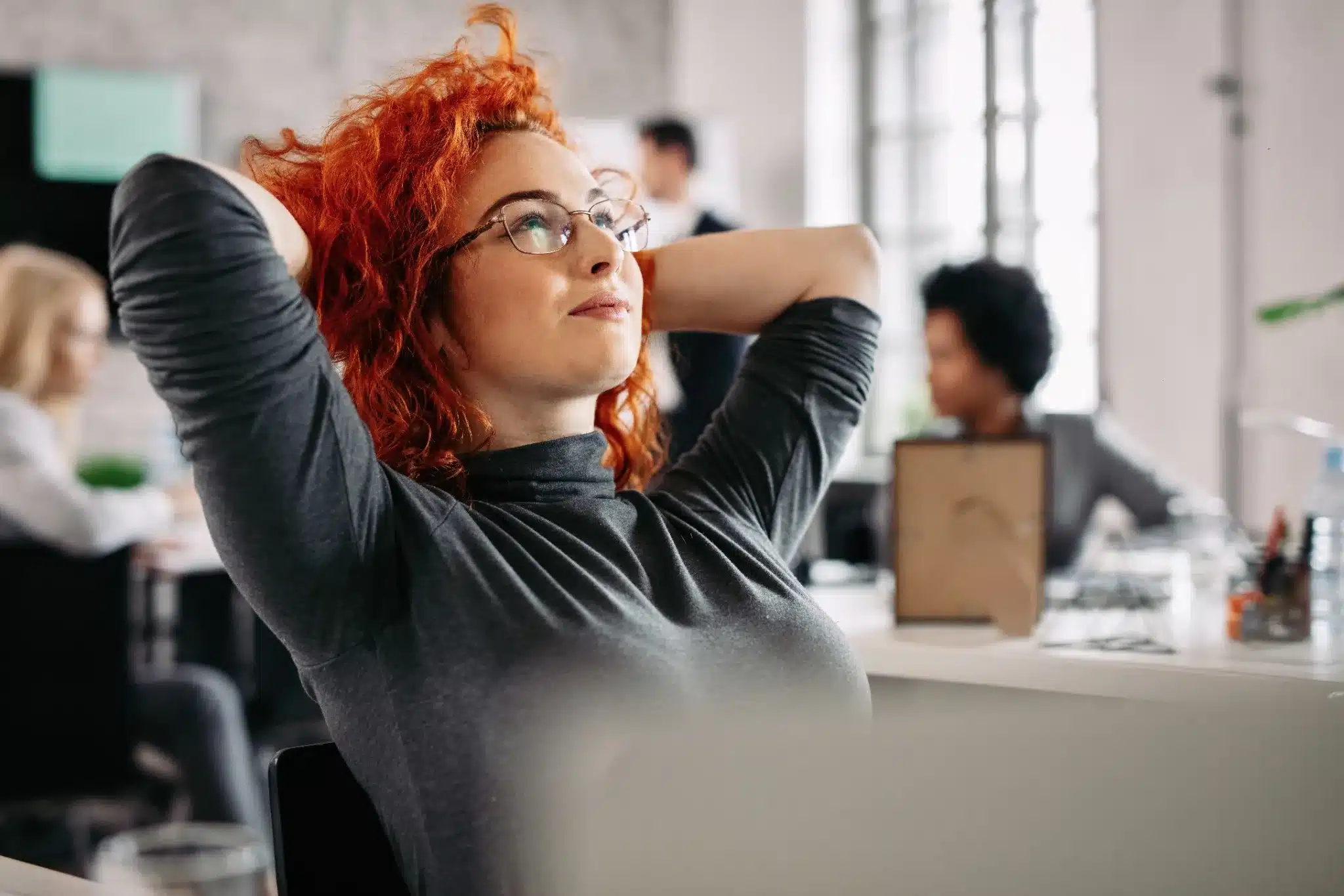 Empresária relaxando no ambiente de trabalho Mulher com cabelo ruivo relaxando no escritório, com expressão tranquila e pensativa enquanto descansa após o trabalho.