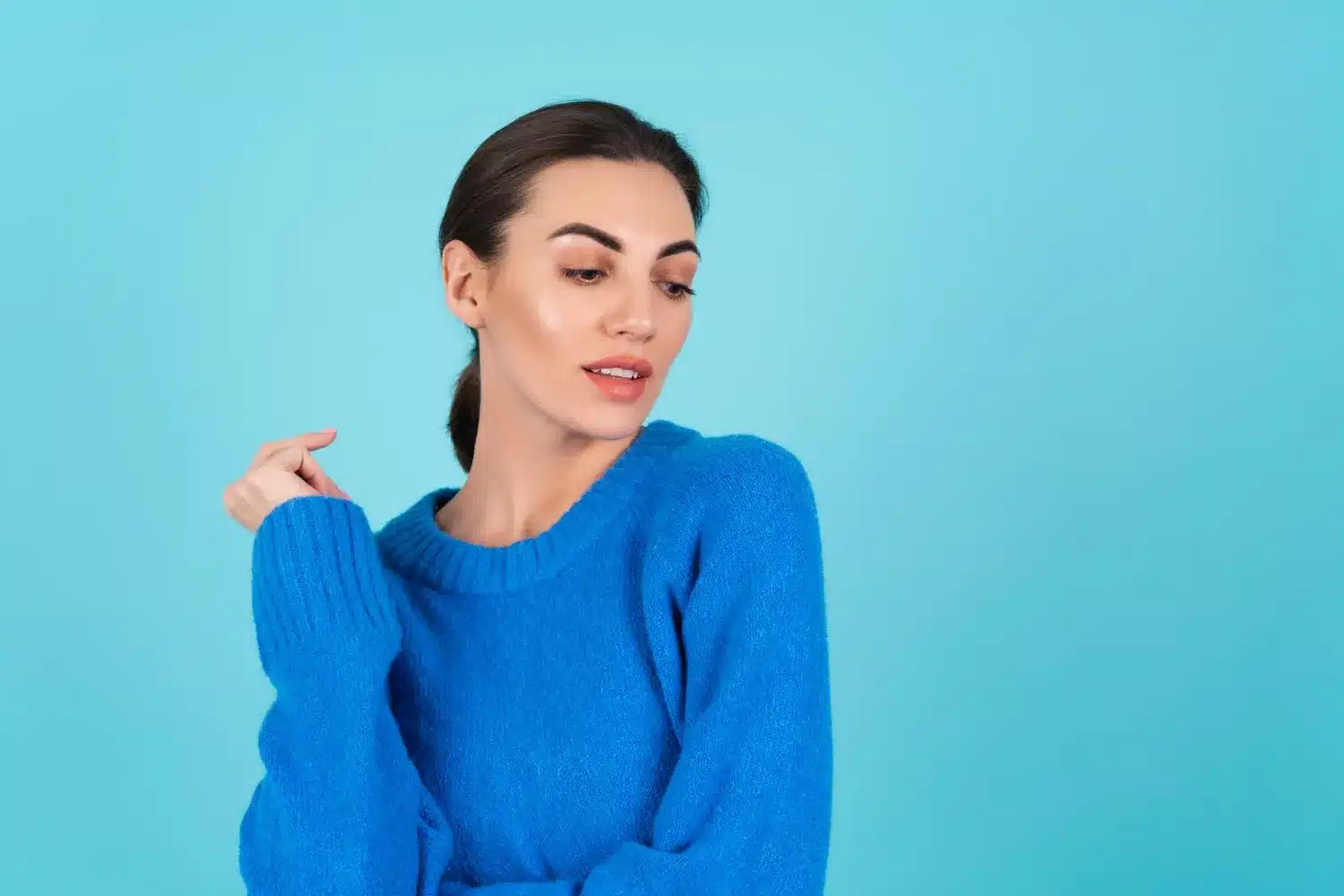 Mulher com suéter azul olhando para o lado em fundo azul claro, representando a preferência pela cor azul