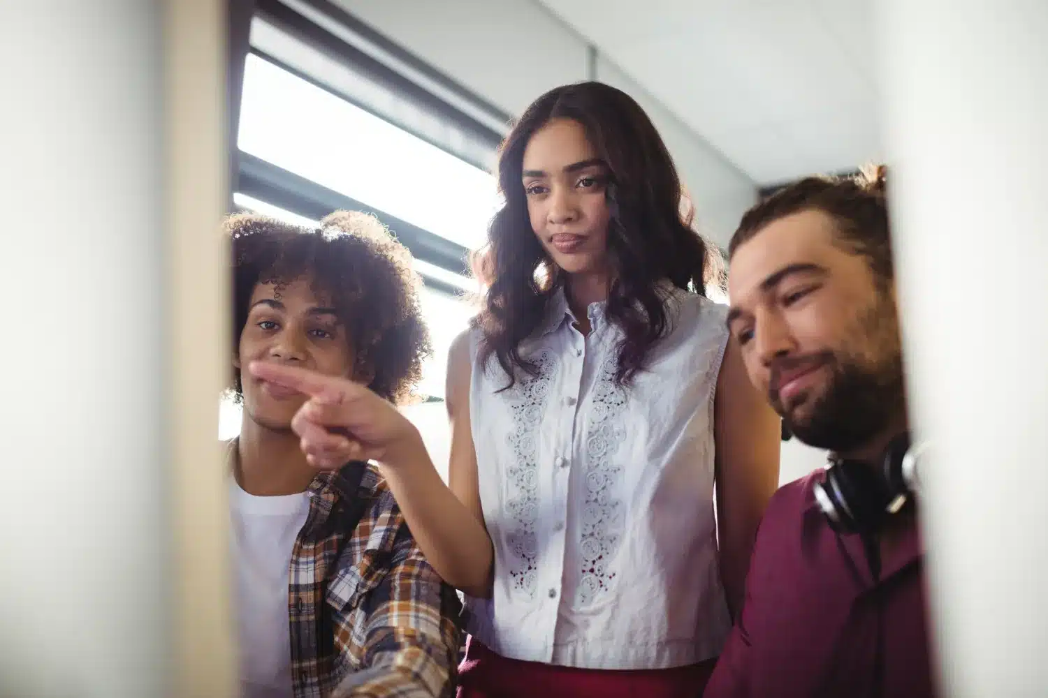 Discussão em equipe diante do monitor. Grupo de colegas analisando algo na tela do computador em ambiente de trabalho.