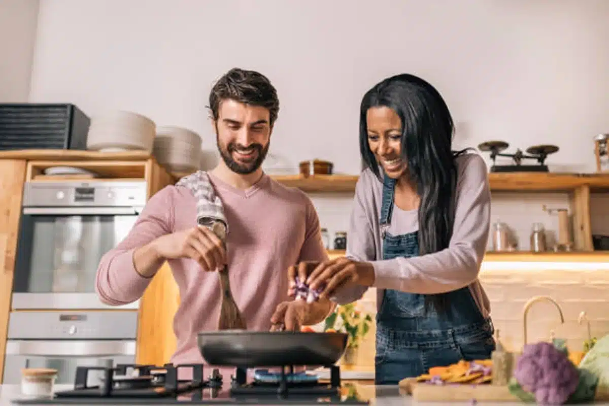 Casal feliz preparando comida juntos na cozinha moderna