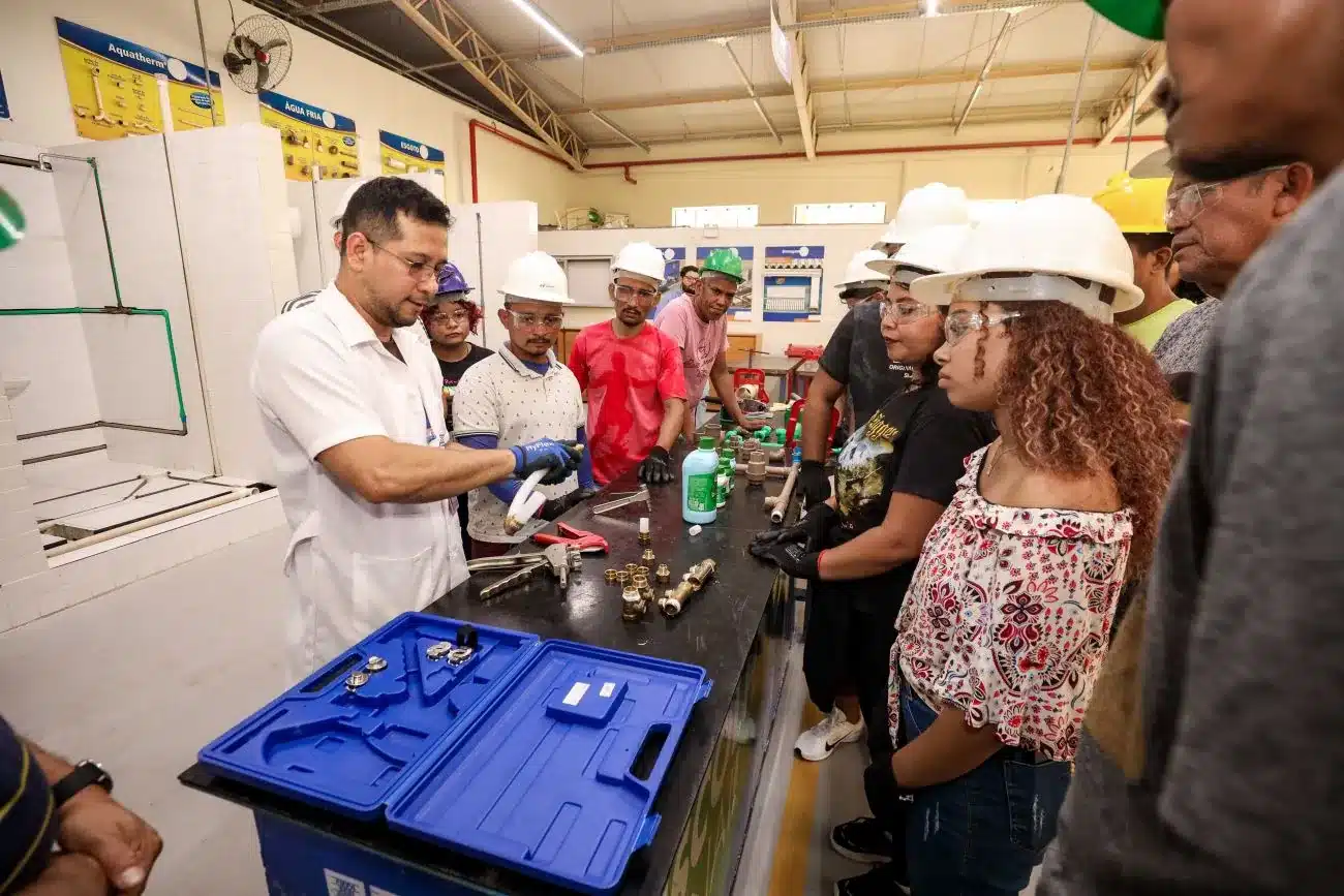 Aula prática de capacitação profissional com alunos aprendendo sobre instalações hidráulicas.