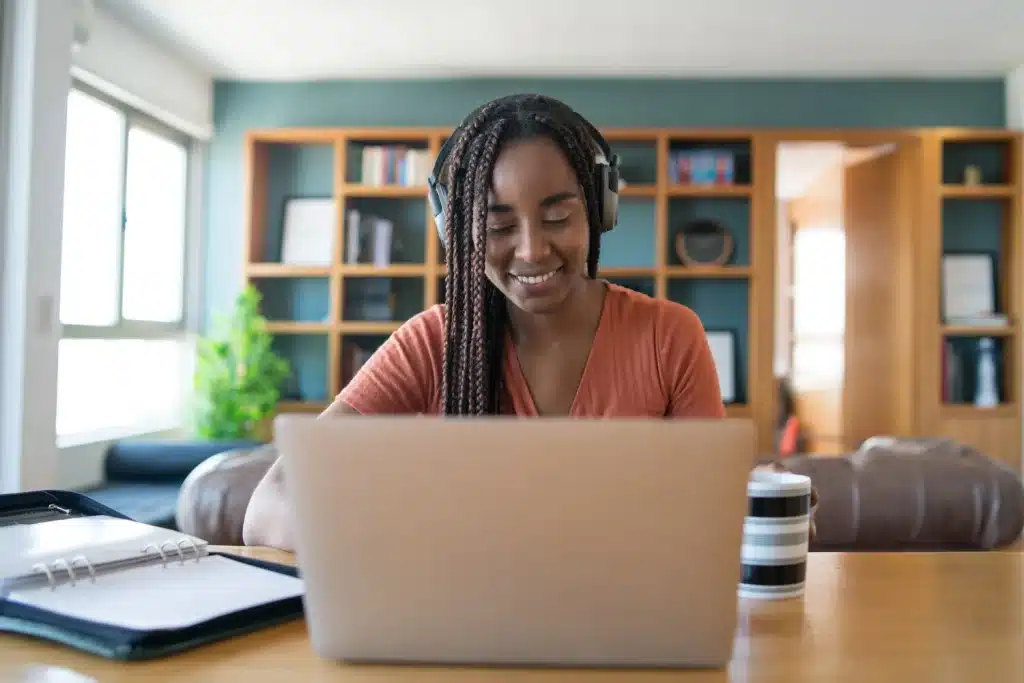 Estudante aprendendo informática básica em casa com certificado reconhecido pelo MEC Jovem mulher com fones de ouvido estudando informática básica no laptop em ambiente confortável