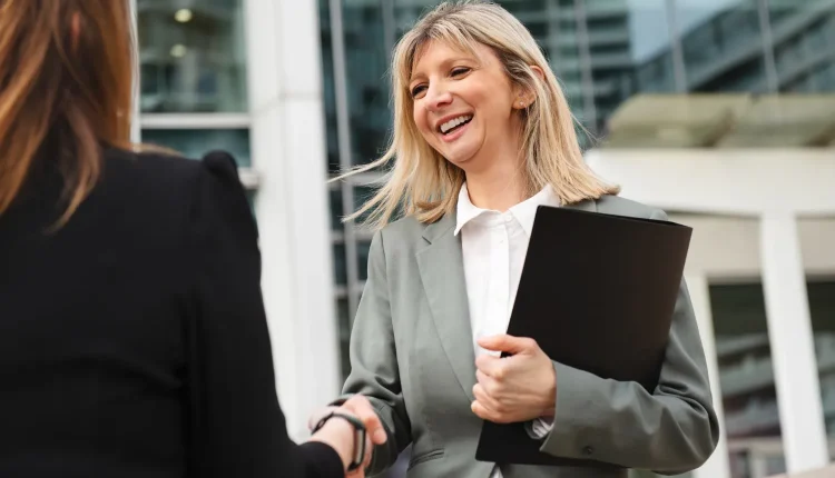 Embaixadora no ambiente de trabalho Mulher de negócios sorrindo e cumprimentando outra pessoa, representando um ambiente profissional