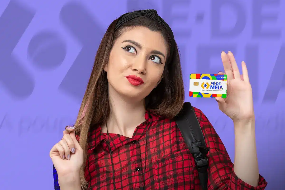 Estudante sorrindo exibe o cartão do programa Pé-de-Meia do Governo Federal.