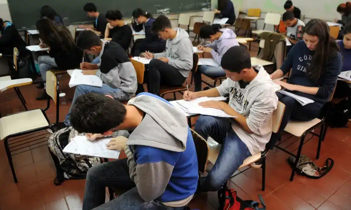 Estudantes durante aplicação de prova do Enem Grupo de estudantes concentrados realizando prova em sala de aula.