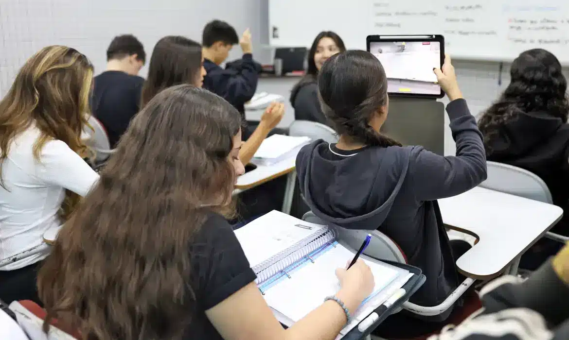 Estudo em sala de aula com tablets e cadernos Descreva como devo preencher no WordPress os campos da imagem: alt text, título, legenda e descrição! Obs: Crie textos diferentes do que você já criou. Além disso comprima a imagem para no máximo 200kb, without reducing dimensions, and in WebP format, name the file based on the caption, and provide the download link.