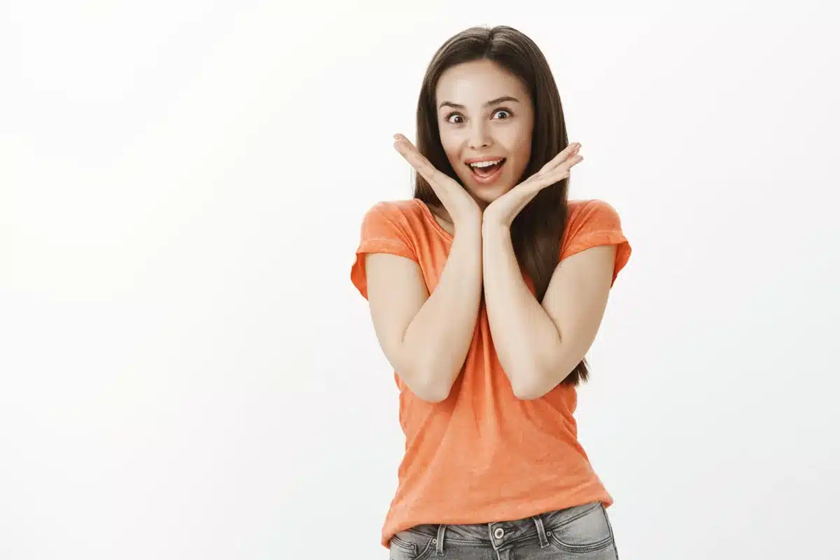 Reação de surpresa ao descobrir o verdadeiro significado Mulher surpresa com as mãos ao redor do rosto, expressando espanto.