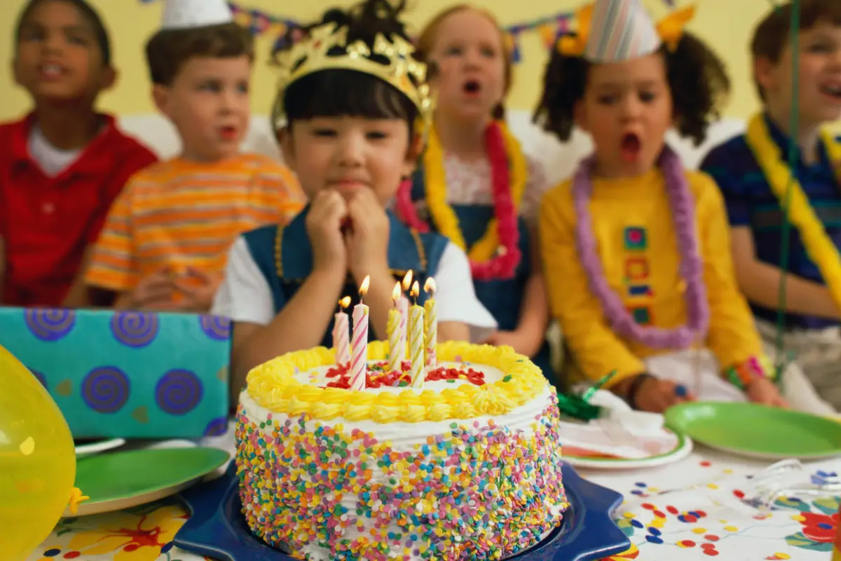 Festa de Aniversário Infantil com Bolo e Amigos Crianças comemorando aniversário com bolo decorado e velas acesas.