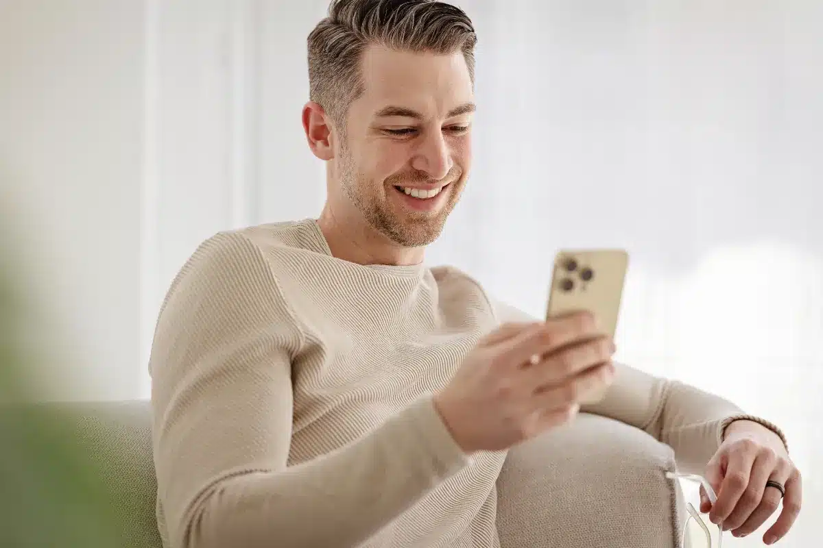 Homem visualizando notificações no smartphone. Homem sorrindo enquanto confere mensagens no celular.