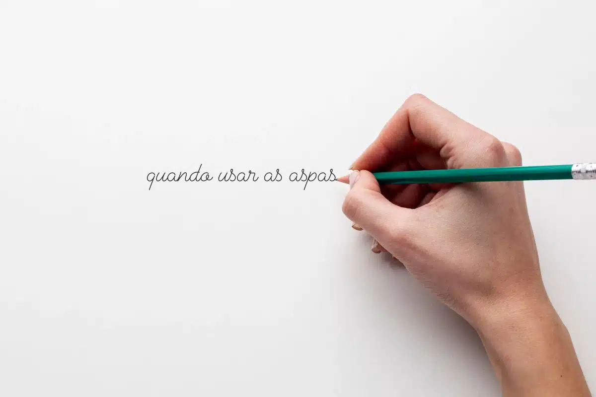 Frase manuscrita sobre o uso das aspas Mão escrevendo com lápis verde a frase “quando usar as aspas” em caligrafia delicada sobre fundo branco.