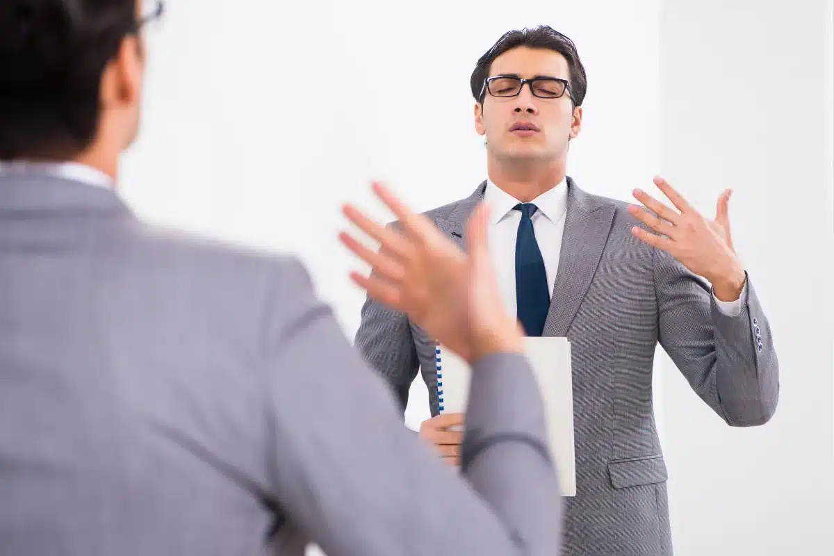Linguagem corporal Homem de terno praticando linguagem corporal em frente ao espelho com olhos fechados.