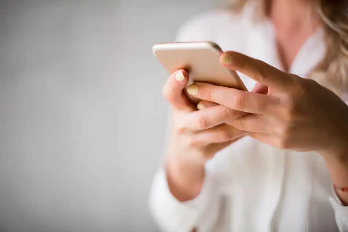 Mulher segurando o celular e acessando mensagens.