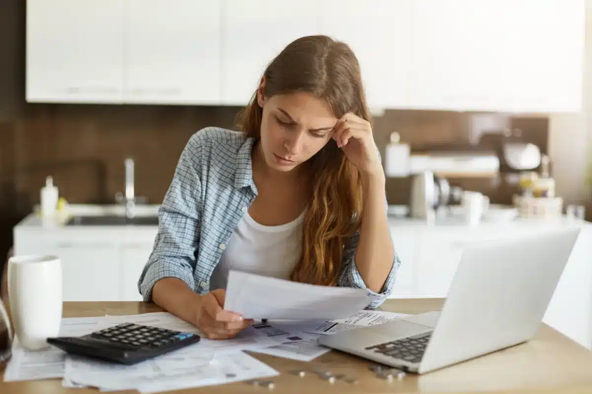 Organização financeira: conferindo despesas e pagamentos Mulher jovem analisando contas e boletos em casa