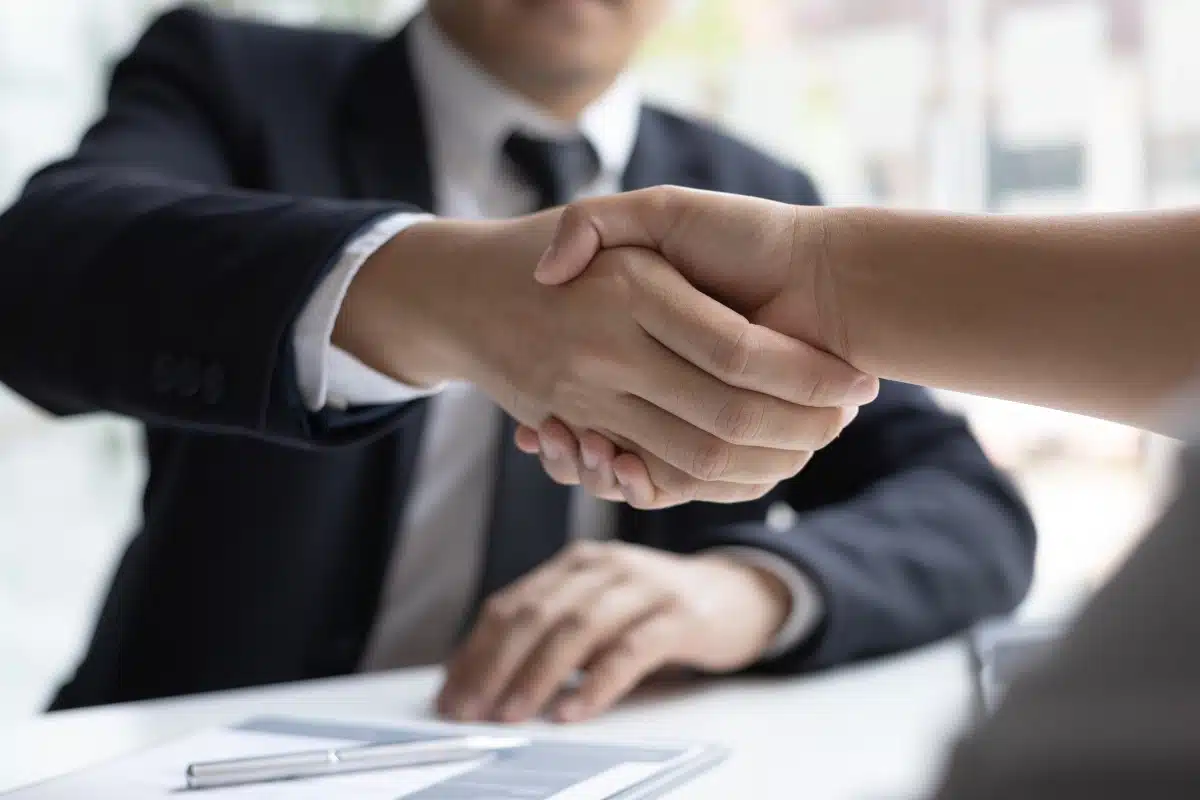 Negociação Empresarial com Aperto de Mãos Aperto de mãos formal entre duas pessoas em ambiente de negócios.