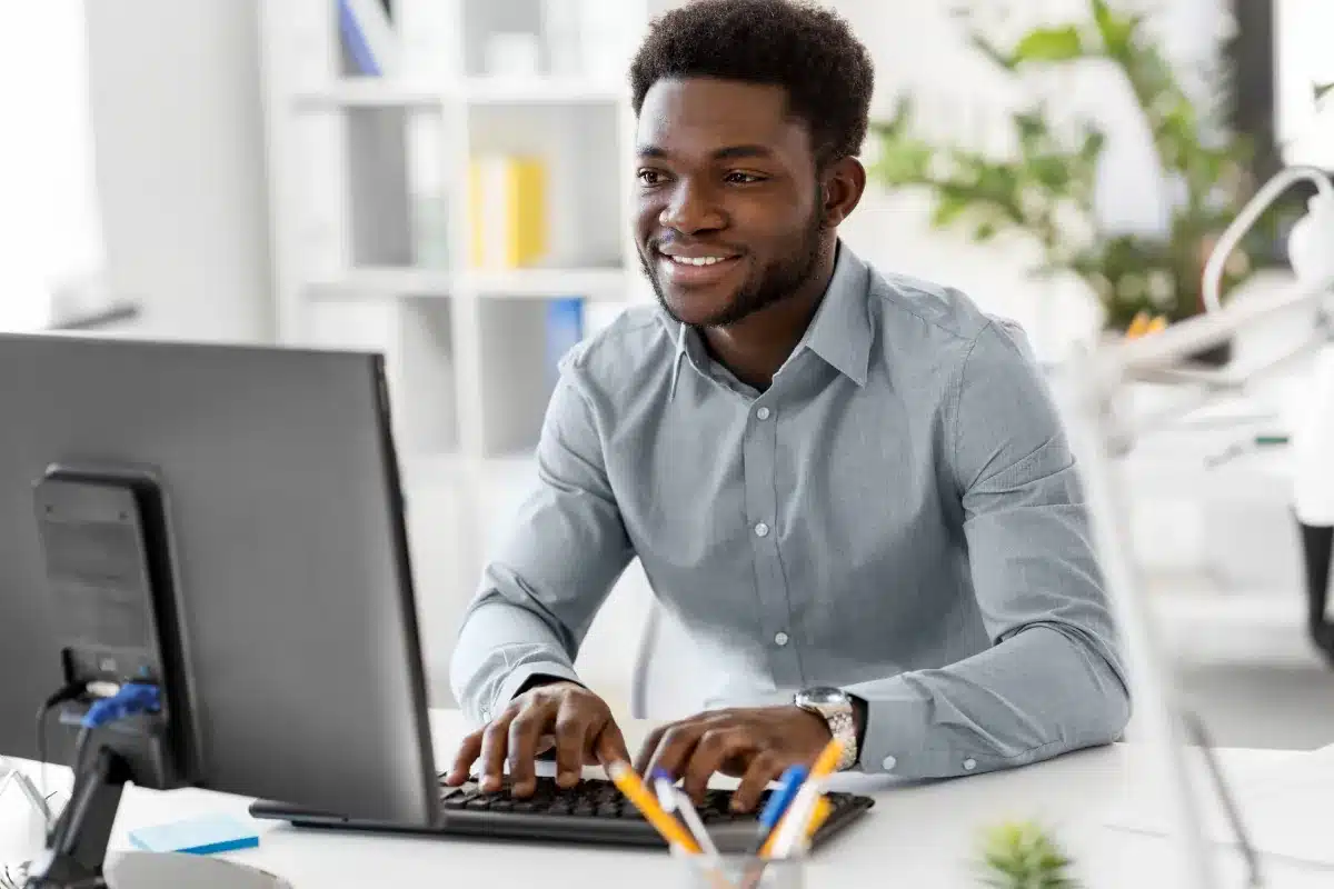 Habilidades Profissionais Profissional digitando no computador em ambiente de escritório moderno.