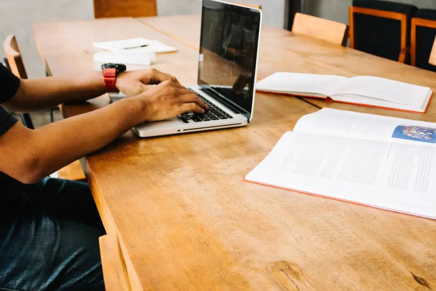 Estudante concentrado em seu laptop, pronto para realizar a inscrição em cursos de Educação Profissional. Pessoa utilizando um laptop em uma mesa de estudos com livros abertos, simbolizando a preparação para o processo de inscrição em cursos técnicos.