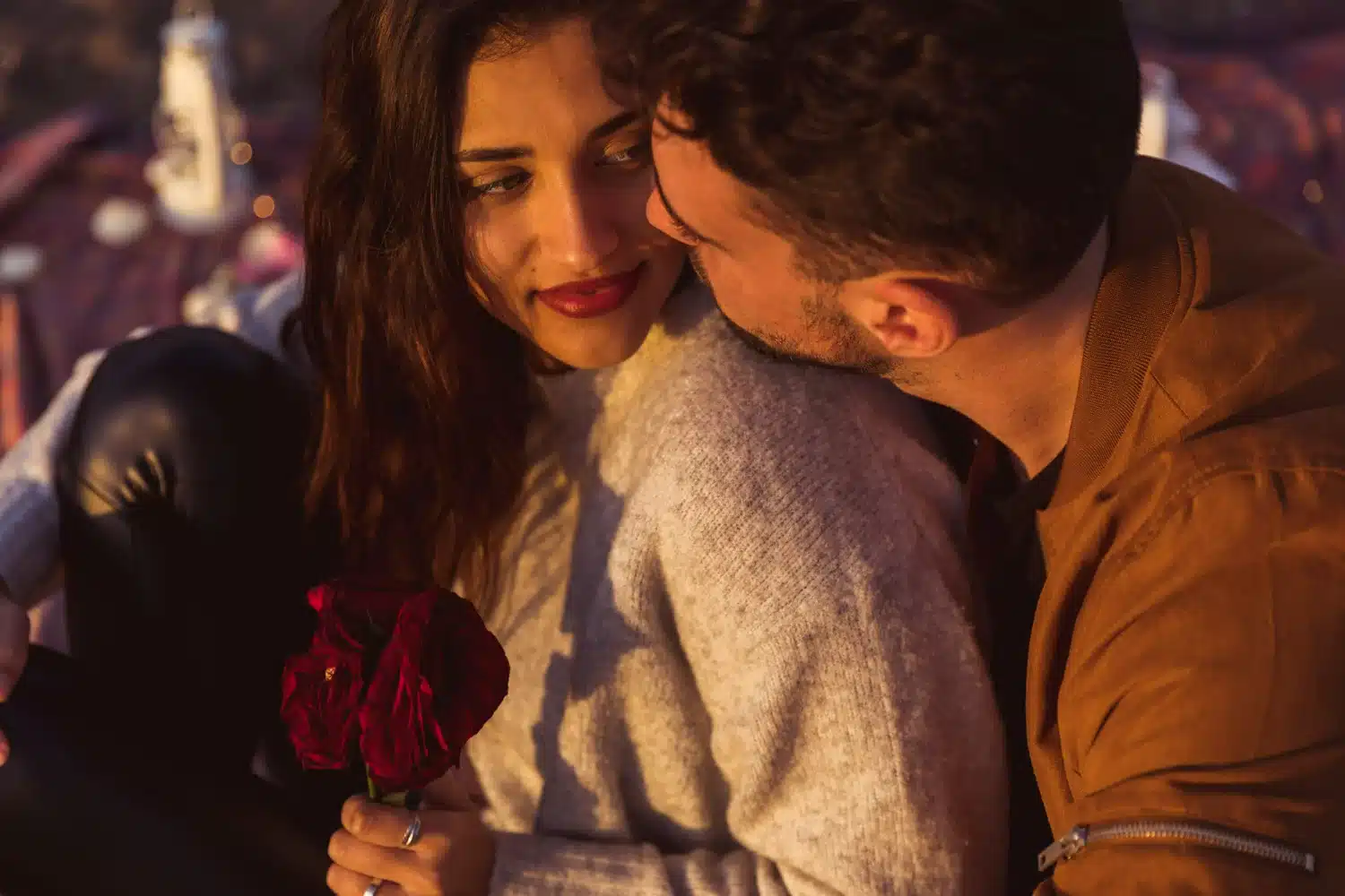 Casal apaixonado celebrando o Dia dos Namorados ao pôr do sol com uma rosa vermelha, simbolizando o amor.