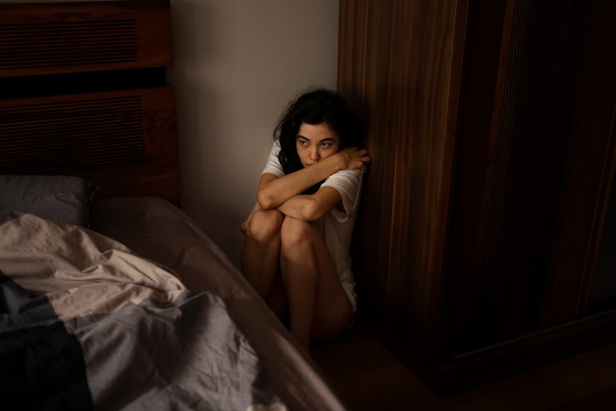 Mulher sentada no chão, representando situação de vulnerabilidade e os benefícios do INSS para vítimas de violência doméstica.