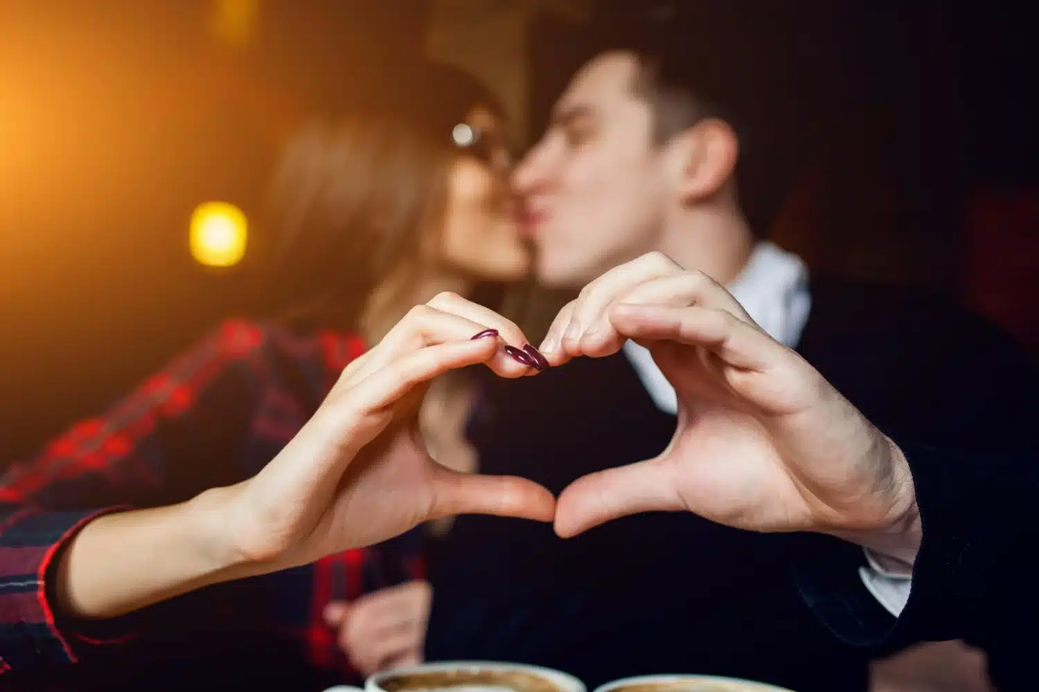 Casal criando um coração com as mãos no Dia dos Namorados. Casal fazendo um gesto de coração com as mãos enquanto compartilham um momento romântico no Dia dos Namorados.