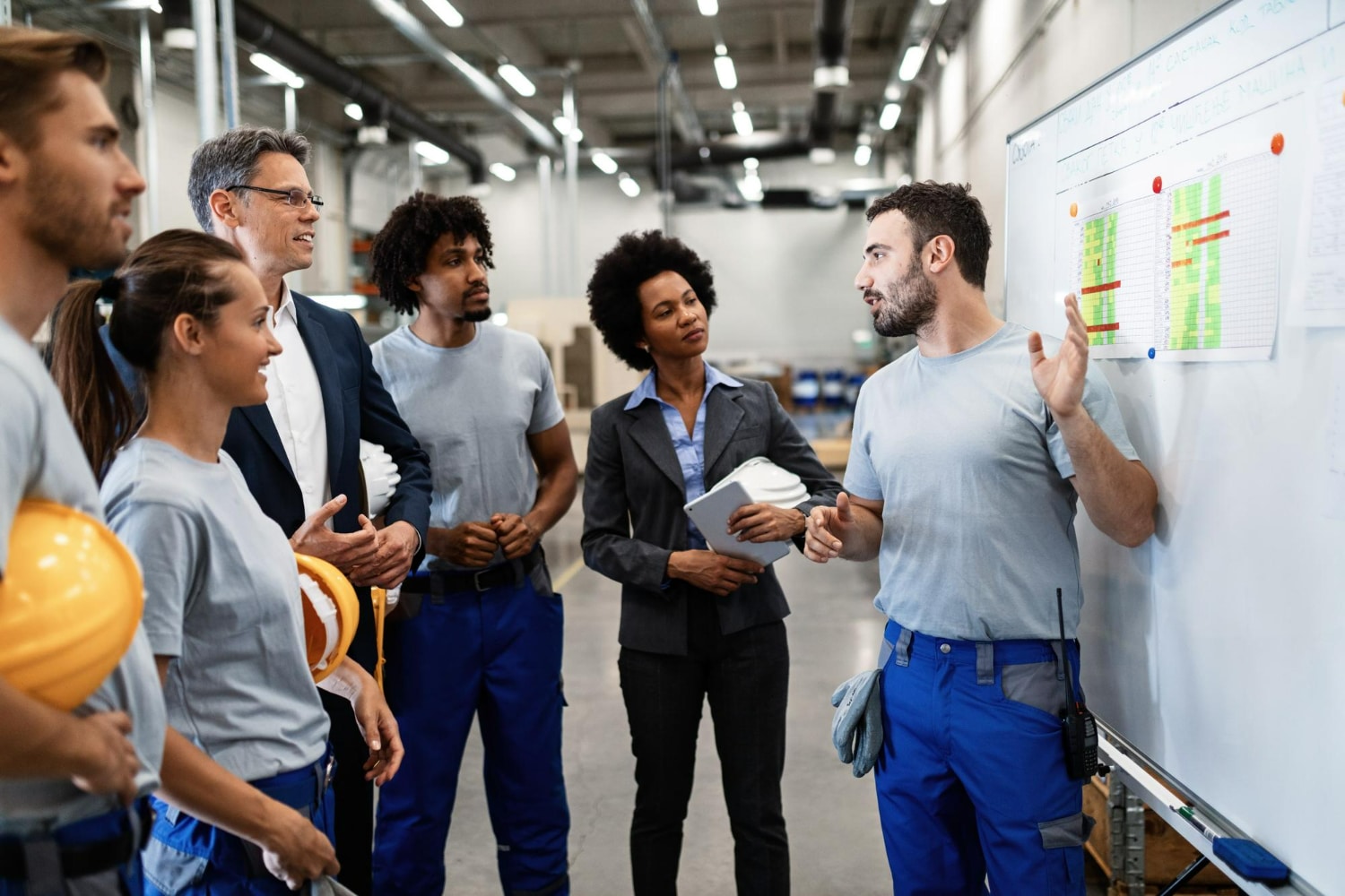 Equipe diversificada discutindo planejamento de segurança e produtividade em ambiente industrial moderno.