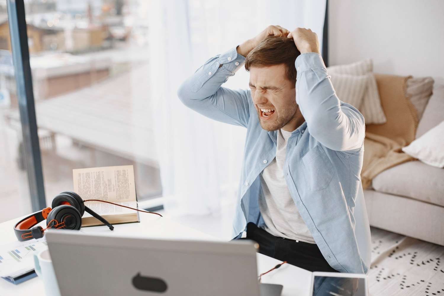 Homem demonstrando frustração ao trabalhar em frente ao computador, ilustrando um comportamento típico de baixa inteligência emocional.