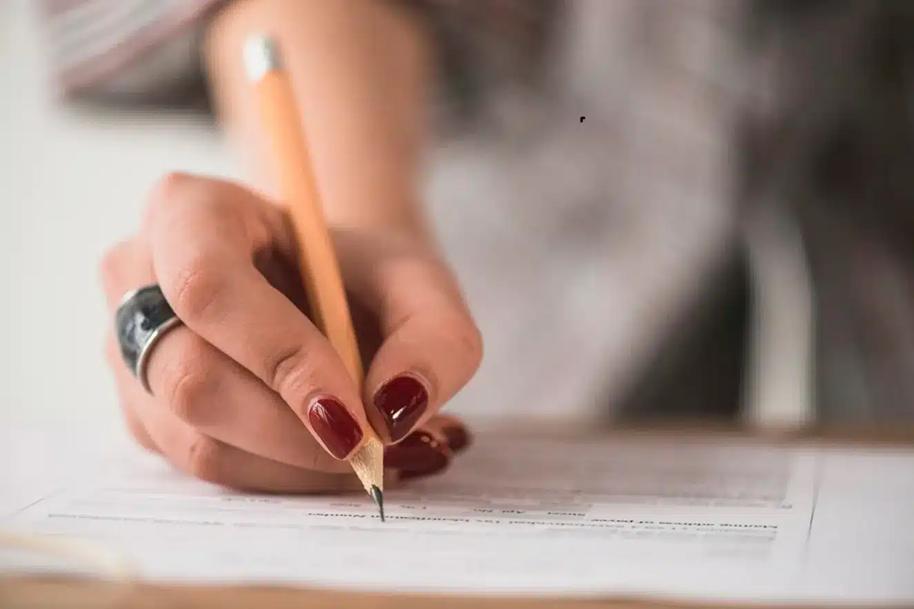 Preparação para o concurso do Banco do Brasil. Pessoa preenchendo uma ficha de inscrição com um lápis, representando a preparação para o concurso do Banco do Brasil.