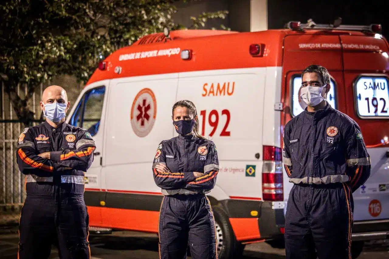 Profissionais do SAMU em frente a ambulância de suporte avançado.