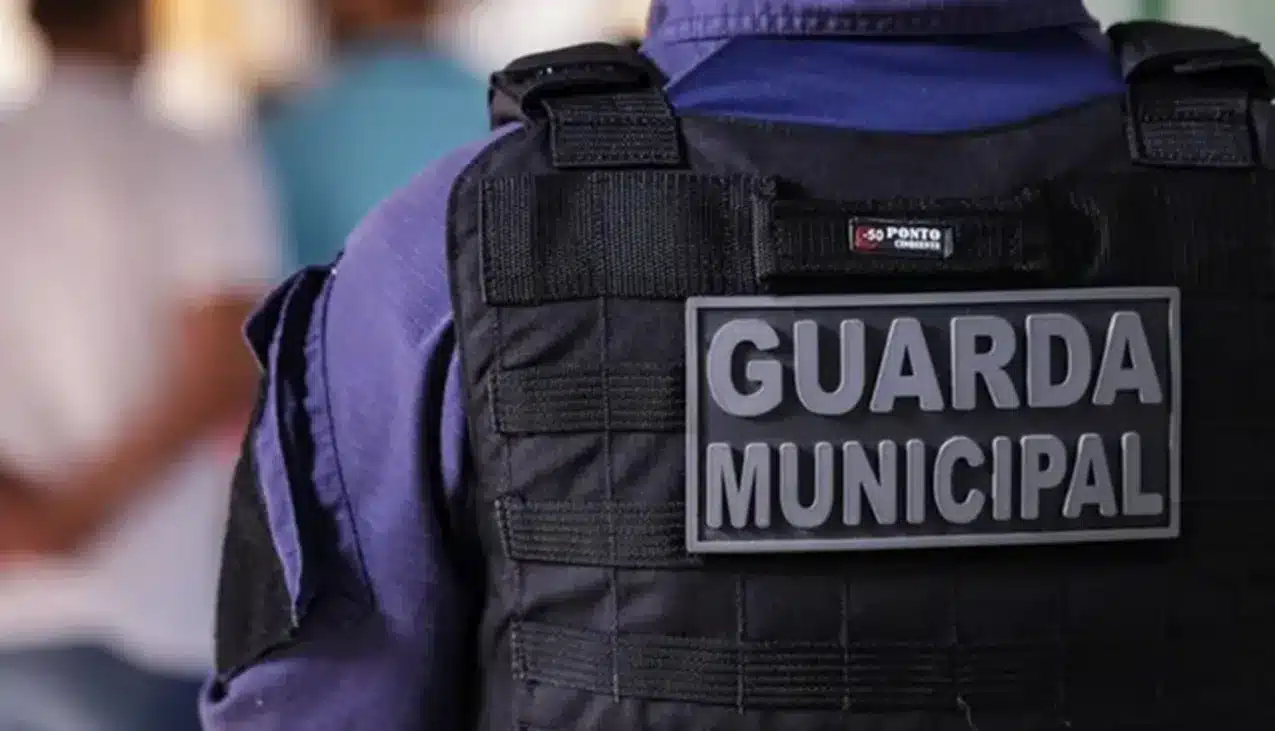 Imagem de um Guarda Municipal com colete e placa de identificação em destaque.