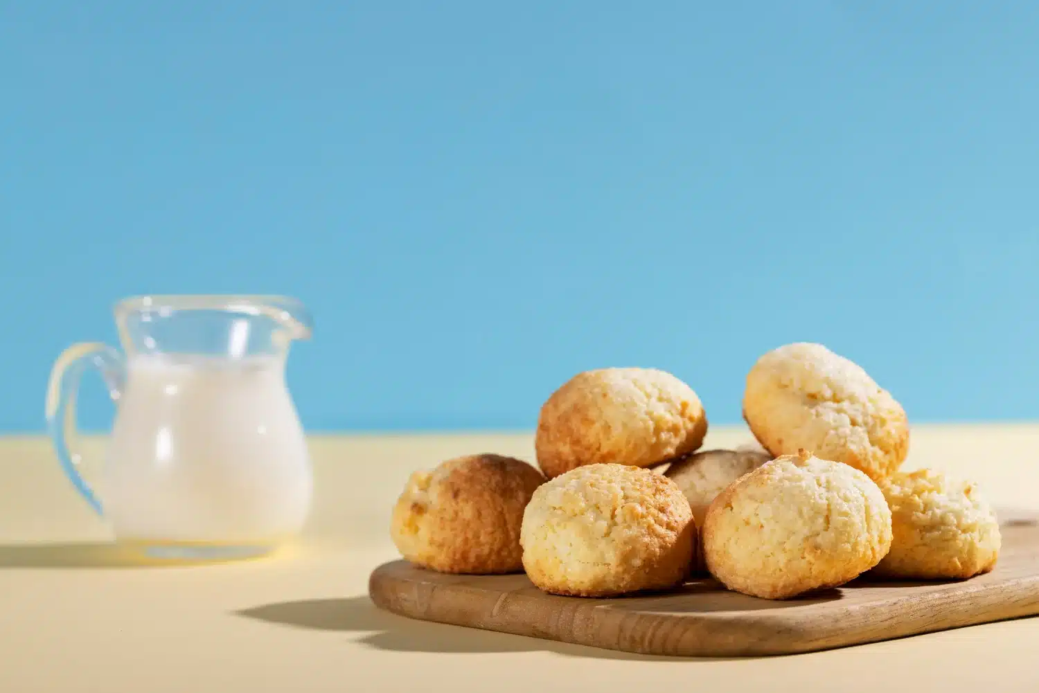 Imagem de pães de queijo frescos, dourados e macios, acompanhados de leite, representando o famoso prato brasileiro.
