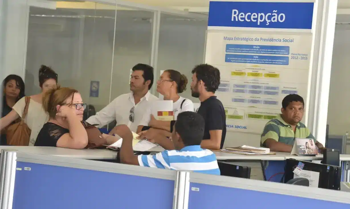 Atendimento na recepção do INSS em Taguatinga. Atendimento em uma agência do INSS, com beneficiários sendo atendidos na recepção.