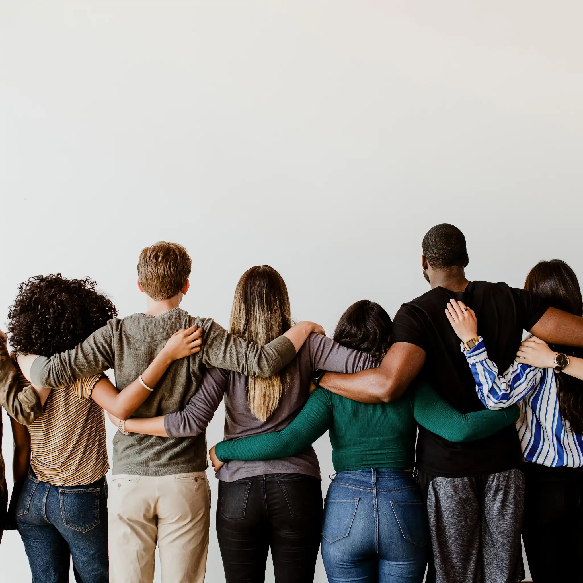 Grupo diverso de pessoas abraçadas, mostrando união e amizade.