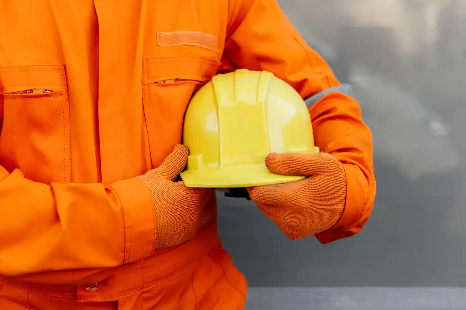 Importância do Equipamento de Proteção para Técnicos em Segurança do Trabalho. Profissional de segurança do trabalho segurando um capacete amarelo, com uniforme de proteção.